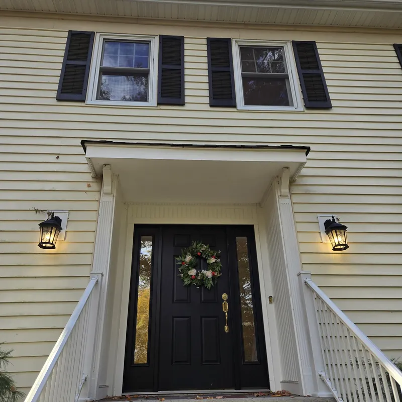 Close-up of a home's front entry with new siding, trim, and light fixtures