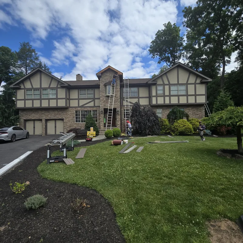 Large stucco and timber Tudor-style home with completed roofing and exterior work
